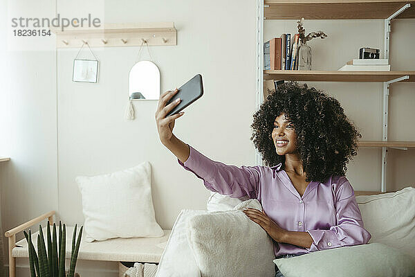 Lächelnde Frau  die zu Hause ein Selfie mit dem Mobiltelefon macht