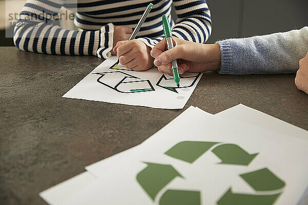 Hände von Mädchen  die Recycling-Symbol mit Stift am Tisch färben