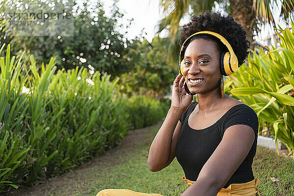 Glückliche Frau mit Kopfhörern  die im Park Musik hört