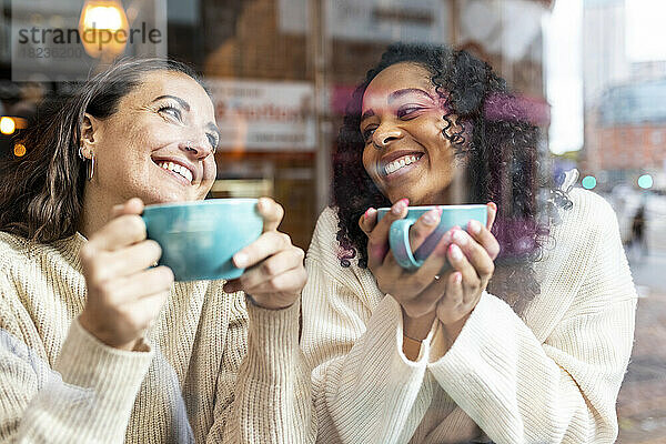 Glückliche Frauen genießen Kaffee im Café  gesehen durch Glas