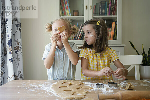 Mädchen bereiten zu Hause Kekse mit Teig auf dem Tisch zu