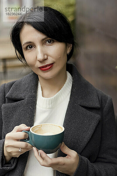 Frau mit rotem Lippenstift hält Kaffeetasse