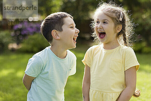 Cheerful girl with brother standing in back yard