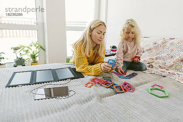 Mutter und Tochter spielen auf dem Bett im Schlafzimmer