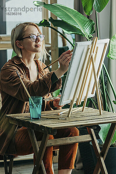 Blonde Frau mit Pinselmalerei auf Leinwand