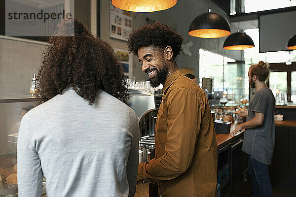 Smiling barista talking with colleague in cafe