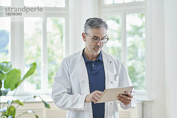 Reifer Arzt nutzt Tablet-PC in der Arztpraxis
