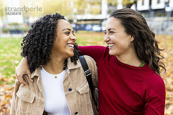 Lächelnde Frau mit Arm um Freundin im Park