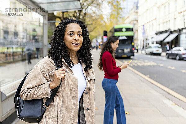Nachdenkliche Frau wartet auf dem Fußweg auf den Bus