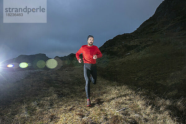 Gefallener Läufer joggt in der Abenddämmerung auf einem Hügel