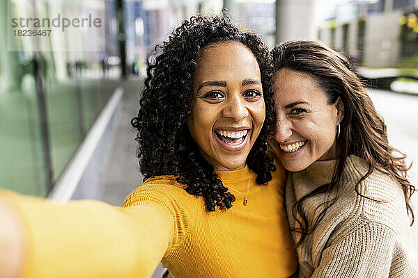 Happy woman taking selfie with friend