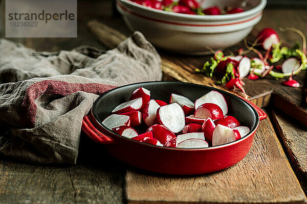 Red radishes in casserole dish at table