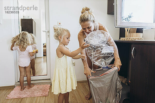 Mother and daughter collecting plastic trash in the kitchen