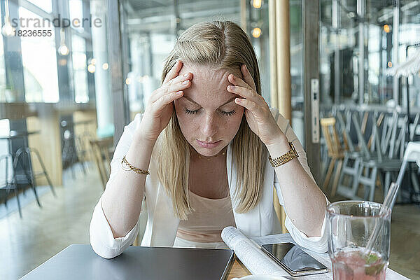 Gestresste Geschäftsfrau sitzt am Tisch im Café