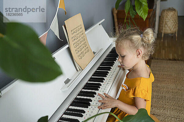 Blondes Mädchen übt zu Hause Klavier