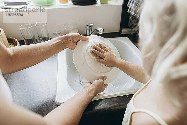 Frau mit Tochter beim Geschirrspülen in der Küche