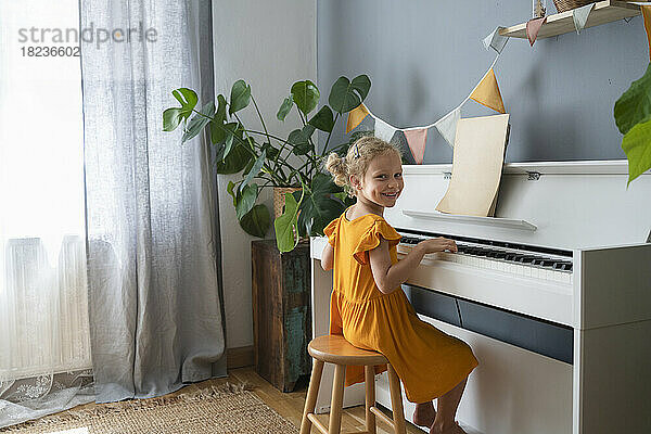 Lächelndes Mädchen  das zu Hause Klavier übt