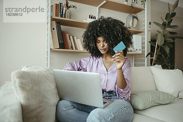 Junge Frau mit Kreditkarte beim Online-Shopping am Laptop zu Hause