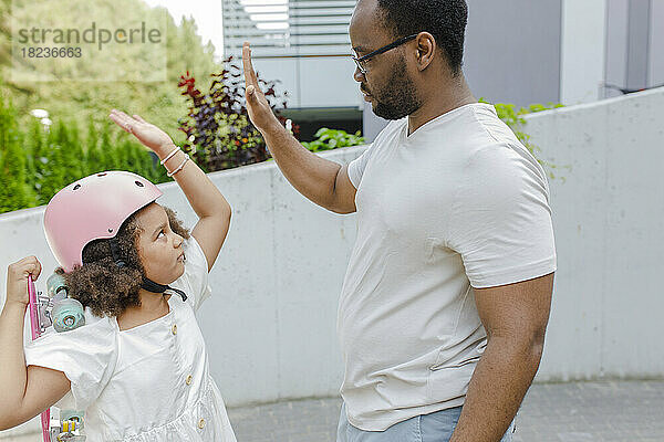 Vater gibt seiner Tochter mit Helm ein High-Five