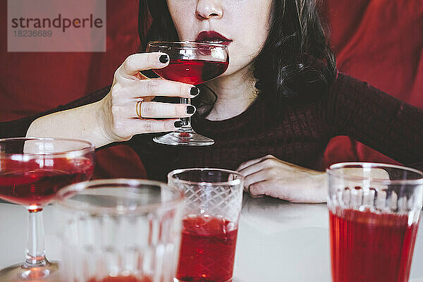 Frau trinkt rotes Getränk am Tisch