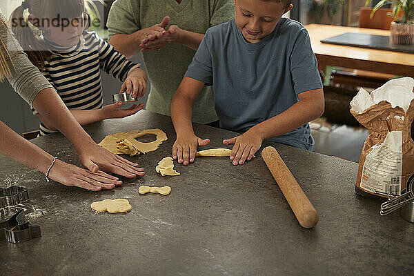 Smiling boy with mother and sisters preparing cookies at home