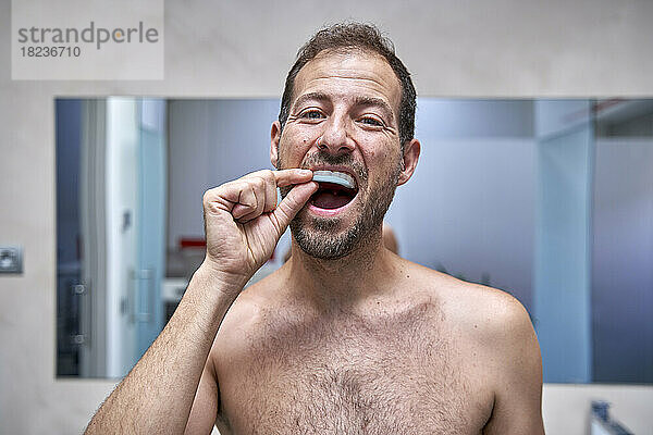 Mann kümmert sich zu Hause im Badezimmer um die Zahnpflege