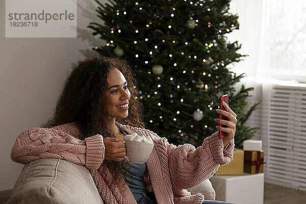 Glückliche Frau  die ein Selfie mit einer Tasse Marshmallow-Kakao macht