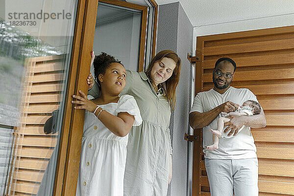 Lächelnde Mutter und Vater stehen mit ihren Töchtern vor der Tür