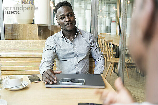 Lächelnder Geschäftsmann bei Treffen mit Kunden im Café