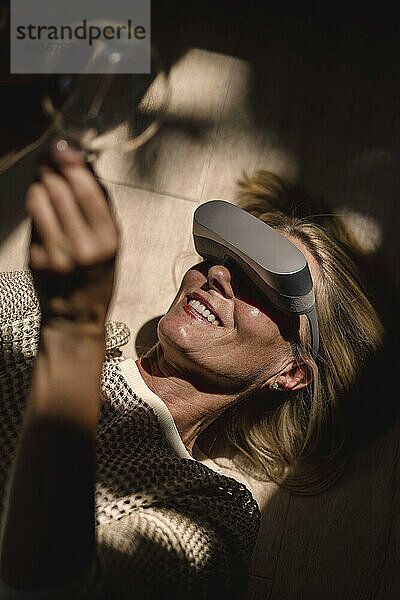 Glückliche Frau mit VR-Brille und Glühbirne mit Sonnenlicht im Gesicht