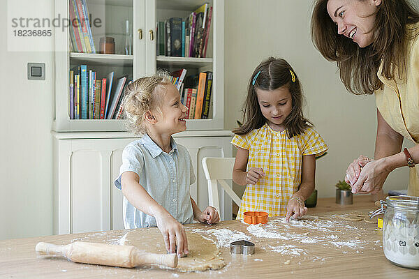 Glückliche Frau mit Mädchen  die zu Hause Kekse zubereiten