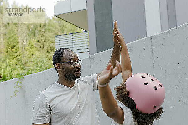 Vater gibt seiner Tochter vor der Wand ein High-Five