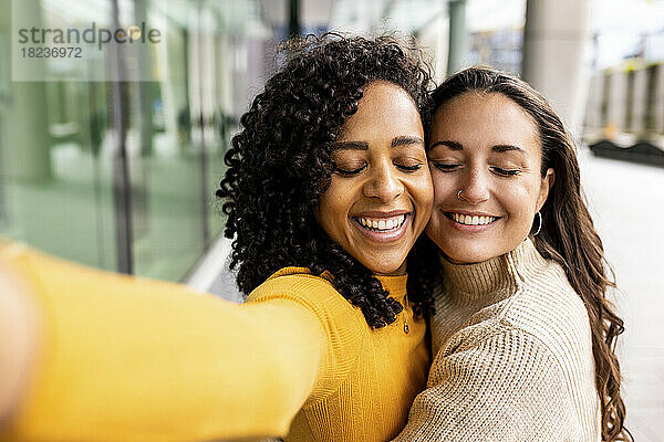 Happy women with eyes closed taking selfie