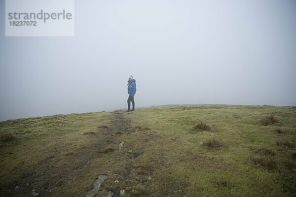 Man standing on hill in foggy weather
