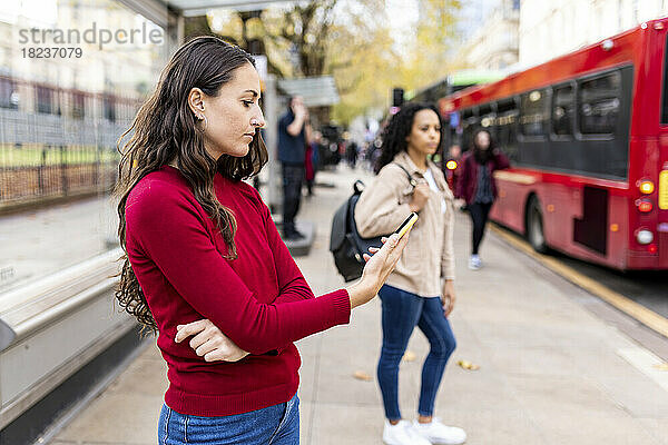 Woman using smart phone at footpath