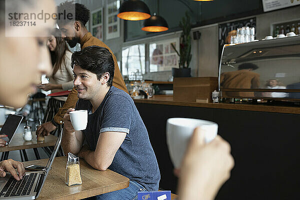 Lächelnder Mann  der Kaffee im Café trinkt