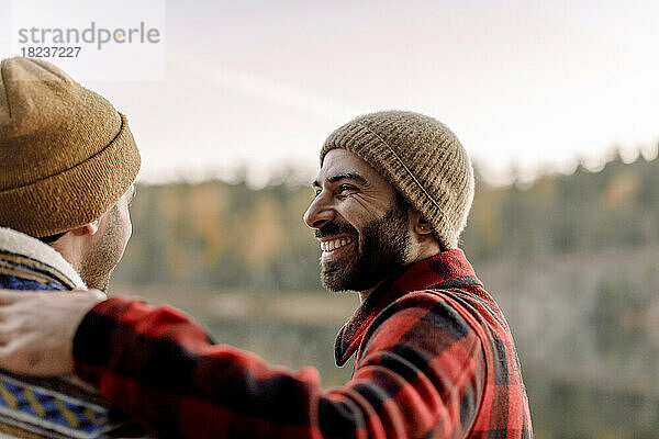 Seitenansicht eines glücklichen Mannes mit Bart  der einen männlichen Freund ansieht