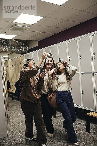 Happy Teenager-Mädchen  die Selfie mit weiblichen Freunden  während in der Schule Korridor genießen