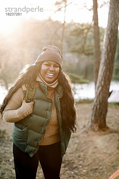 Porträt einer glücklichen jungen Frau im Wald stehend