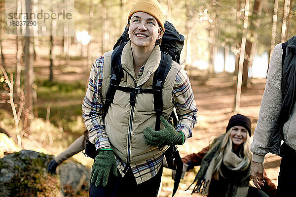 Glücklicher Mann  der beim Wandern mit Freunden im Wald wegschaut