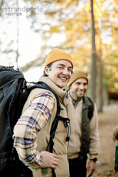 Seitenansicht eines glücklichen jungen Mannes mit Rucksack durch einen männlichen Freund