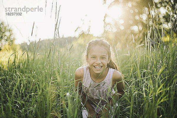 Porträt eines glücklichen Mädchens  das an einem sonnigen Tag im Gras spielt