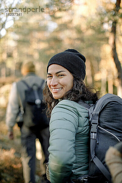 Glückliche Frau schaut beim Wandern im Wald über die Schulter