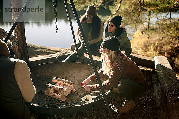 Freundinnen unterhalten sich beim Campen  während sie eine Feuerstelle vorbereiten