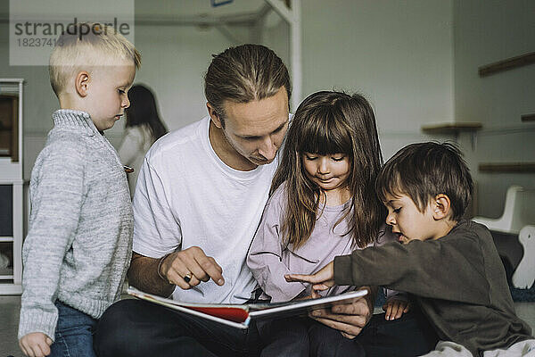 Lehrerin liest mit Schülern in der Kindertagesstätte ein Märchenbuch