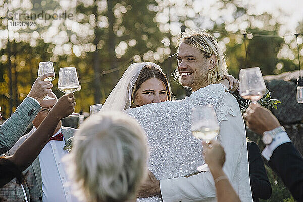 Lächelndes frisch vermähltes Paar tanzt inmitten von Familie und Freunden bei der Hochzeit