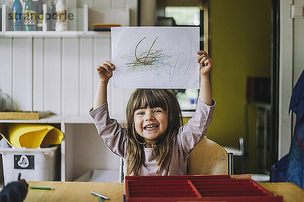 Porträt eines glücklichen Mädchens  das mit Buntstift auf Papier im Kindergarten kritzelt