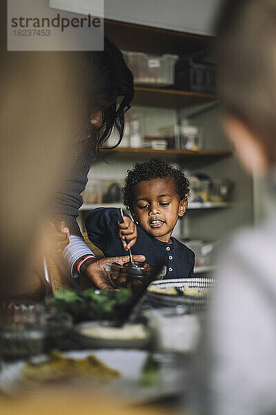 Eine Lehrerin serviert einem Jungen beim Frühstück im Kindergarten das Essen