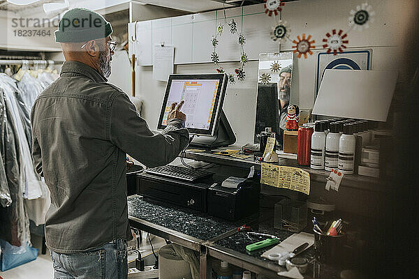 Rückansicht eines männlichen Schneiders am Computer in einer Werkstatt