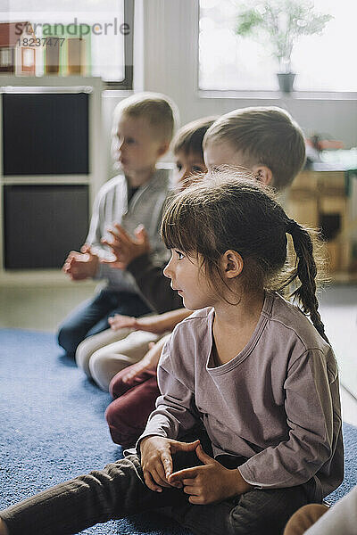 Rassisch gemischte Kinder sitzen im Kindergarten auf einem Teppich
